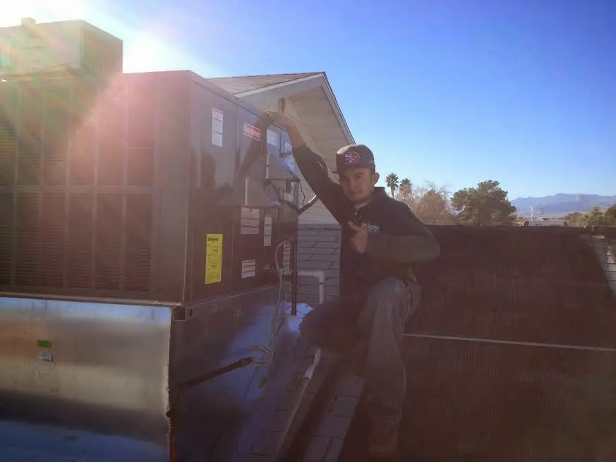 HVAC technician performing AC Tune-Up on a rooftop unit in Atkinson